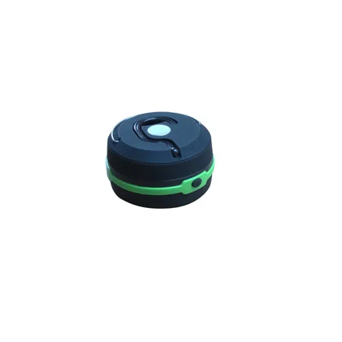 Un dispositivo redondo, compacto, de color negro y verde que cuenta con un botón central y un pequeño indicador luminoso en el lateral. Este dispositivo, similar a la Lampara / Linterna Compacta 60 Lum 1W Quail, está diseñado para ser portátil y fácil de usar en diversas aplicaciones.