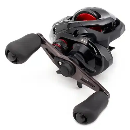 Un carrete de pesca con baitcasting Carrete Horizontal Shimano Caenan A 151 Left Hand - Cae151a negro y rojo con manijas ergonómicas dobles y una marca de relación de transmisión de 6.3:1 presenta un diseño elegante y está fotografiado sobre un fondo blanco liso.