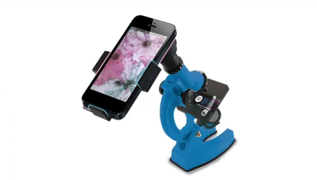 Un microscopio Konus Konustudy-4 900x de color azul intenso con un accesorio para teléfono inteligente, que muestra una imagen rosa y gris ampliada en la pantalla del teléfono.