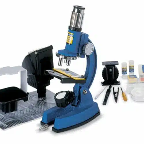El microscopio Konus Konuscience 100x - 1200x en color azul incluye una gama de accesorios como portaobjetos, pinzas, una placa de Petri y una lupa, todos ellos perfectamente expuestos sobre un fondo blanco.