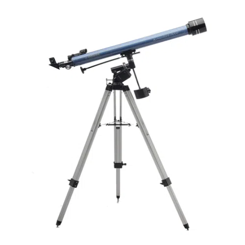 El telescopio refractor Konus Konustart 900b 1738 con acabado plateado y azul está montado sobre un trípode plateado. El telescopio está ligeramente inclinado hacia arriba y cuenta con una lente ajustable con perillas de ajuste fino. El trípode tiene tres patas extensibles y una plataforma de apoyo debajo del telescopio.