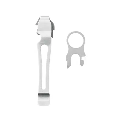 Sobre un fondo blanco se muestra un clip de bolígrafo plateado y un accesorio de bucle de metal con muescas, que recuerda al diseño elegante que se encuentra en herramientas como la Multiherramienta Charge Plus Leatherman 832516. El clip tiene una parte superior en forma de gancho y un cuerpo alargado y angosto, mientras que el accesorio de bucle es circular con dos pequeñas extensiones.