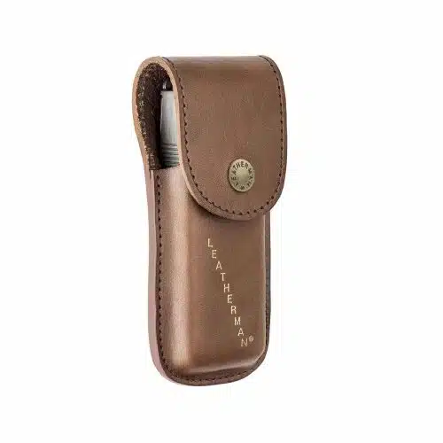 Una bolsa de cuero marrón con cierre de botón a presión, con el logotipo "Leatherman" grabado en letras doradas en el costado. Esta bolsa Funda Leatherman Heritage 832594 parece contener una herramienta multiusos.