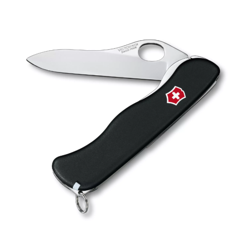 Se muestra una Cortapluma Sentinel One Hand Negra Victorinox 0.8413.M3, parcialmente desplegada con una hoja extendida. La navaja tiene un elegante mango negro con un emblema de cruz roja y blanca y un pequeño llavero adherido a la base del mango.
