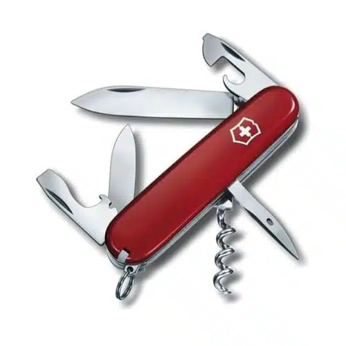 Una navaja suiza roja, identificada como Cortapluma Victorinox Spartan Roja 1.3603, muestra múltiples herramientas, entre ellas una hoja grande, una hoja más pequeña, un abridor de botellas con un destornillador de punta plana, un abrelatas, un sacacorchos y un escariador. El mango de la navaja presenta el emblemático emblema de la cruz blanca.