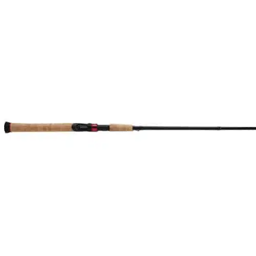 La Caña Shimano Sojourn 602medspin 1.80m es una caña de pescar negra y marrón que presenta un mango de corcho y un detalle rojo cerca del portacarrete, mostrado horizontalmente sobre un fondo blanco.