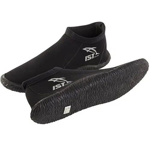 Un par de botas de buceo de neopreno negras, comercializadas como Zapato De Buceo Ist S38- 3mm Neopreno, con suelas de goma texturizadas. Una de las botas está en posición vertical, mostrando de forma destacada el logotipo de IST en un lateral, mientras que la otra se encuentra de lado, revelando el intrincado patrón de la suela.