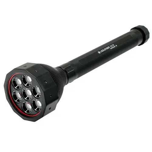 Linterna Led Lenser X21r negra de 5000 lm de alta resistencia con cuerpo cilíndrico y cabezal ancho. El cabezal tiene siete bombillas LED dispuestas en un patrón circular con un anillo rojo alrededor de ellas y el cuerpo tiene un agarre texturizado. El nombre de la marca está impreso en el costado del cuerpo.