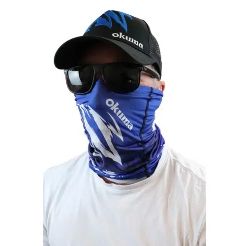 Una persona lleva una máscara de pesca Bandana Okuma con protección solar en tonos azules y diseños blancos junto con el logotipo de "Okuma". También lleva gafas de sol oscuras, una gorra negra con detalles en azul y blanco y una camisa blanca.