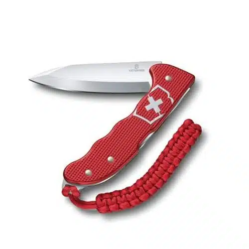 Navaja suiza Hunter Pro Alox Rojo Victorinox 0.9415.20 Cortapluma roja con la hoja extendida. El mango presenta un emblema de cruz blanca y viene con un paracord rojo unido al extremo. La hoja es afilada y metálica, en contraste con el mango rojo texturizado, que encarna la precisión de la serie Hunter Pro.