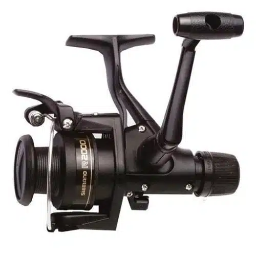 El Carrete Shimano IX es un carrete de pesca negro que cuenta con una empuñadura suave y un mecanismo de engranajes preciso. La bobina, etiquetada como "R2000", garantiza una fácil liberación y recuperación de la línea gracias a su brazo de agarre. Este diseño robusto es ideal para diversas actividades de pesca.
