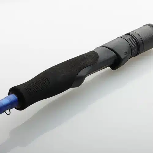 La imagen en primer plano del mango de la caña de pescar Caña Savage SGS4 Specialist 2,74m resalta su empuñadura texturizada en negro y gris acentuada por una línea azul, lo que refleja un diseño elegante. Colocada en diagonal sobre un fondo gris claro, rezuma precisión y estilo.