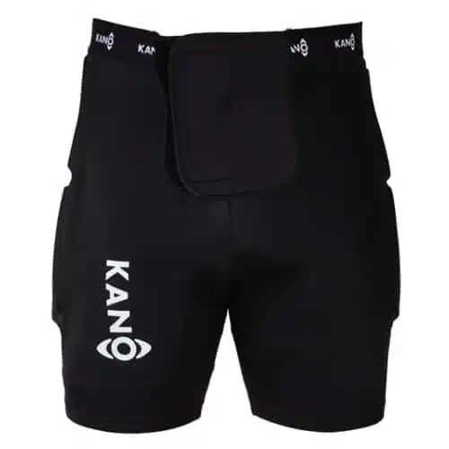 Un par de calzas con protección Kano, que presentan un diseño de compresión negro con el nombre de la marca "KANO" impreso verticalmente en blanco en el muslo izquierdo. La pretina muestra el logotipo "KANO" repetidamente en blanco sobre un fondo negro. Estas calzas están diseñadas con un panel frontal acolchado para una protección adicional.
