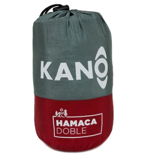 Una vibrante bolsa de transporte en rojo y gris, con cordón, está adornada con el nombre del producto "Hamaca Doble Rojo Kano", junto con un encantador dibujo de árboles y una hamaca.