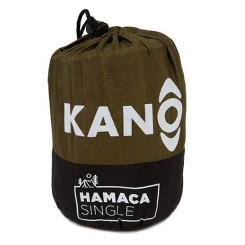 La Hamaca Single Verde Camo Kano es una bolsa cilíndrica compacta en verde oliva y negro que muestra de forma destacada "KANO" junto con un logotipo en la sección superior. Debajo, "HAMACA SINGLE" está enmarcado por símbolos de árboles y tiendas de campaña. La parte superior está asegurada con un cordón, lo que enfatiza su diseño duradero como hamaca individual.