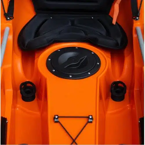 Primer plano de la zona de asientos de un Kayak Scupper 12 Swell naranja, en el que se destaca un asiento acolchado negro y una trampilla circular en la parte delantera. A cada lado hay dos portavasos, con cordones elásticos negros cerca de la parte inferior de la imagen, que muestran una combinación de funcionalidad y estilo.