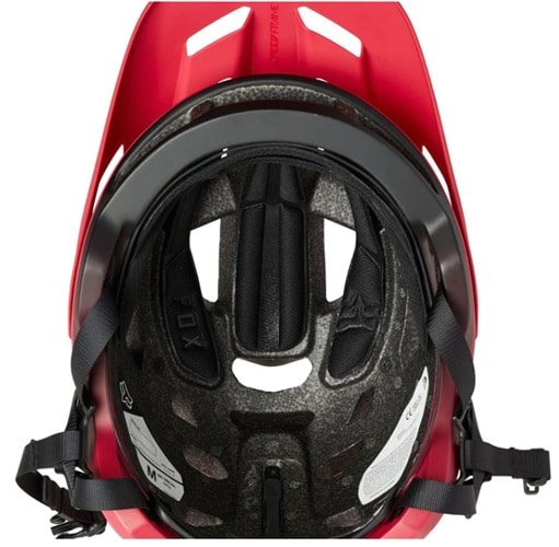 El casco de bicicleta Speedframe Mips Fox Rojo se muestra desde abajo, dejando al descubierto el acolchado interior, los orificios de ventilación y las correas ajustables. En posición vertical, el casco muestra la etiqueta de talla y los detalles de diseño para una máxima protección y comodidad.