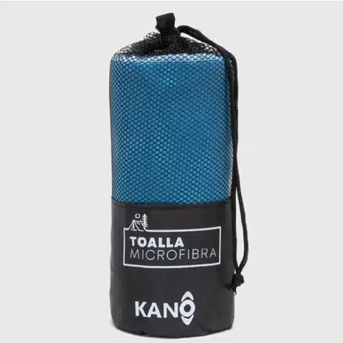 Una Toalla Microfibra Kano azul enrollada se encuentra parcialmente dentro de un estuche de malla negra. El estuche de transporte tiene un cierre con cordón y está etiquetado con texto blanco que dice “Toalla Microfibra” y la marca “Kano”. El fondo es blanco liso.
