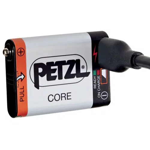La Batería Recargable Petzl Accu Core está conectada a un cable de carga, mostrando sus indicadores de estado: "On" indicado en negro, "Ready" mostrado en verde y "Charge" mostrado en rojo.