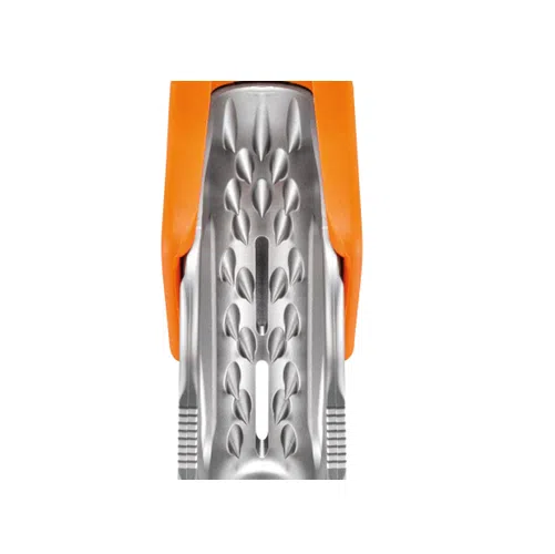Primer plano del Bloqueador de Emergencia Petzl Tibloc, que presenta un diseño metálico con un patrón dentado y texturizado y dos empuñaduras de plástico de color naranja. El objeto tiene una superficie lisa y brillante adornada con varias formas y líneas geométricas.