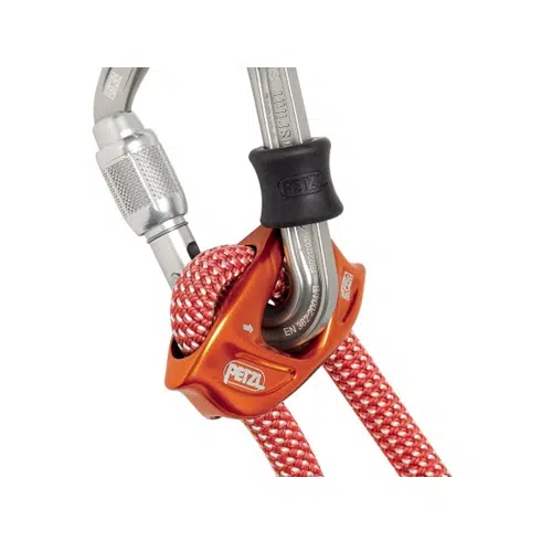 Un primer plano de una instalación de escalada muestra el sistema Cabo de Anclaje Petzl Dual Connect Adjust, que incluye un dispositivo de seguridad rojo con una cuerda blanca y roja enhebrada a través de él, sujeta de forma segura a un mosquetón plateado.