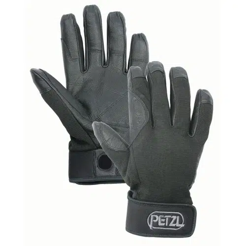 Se muestra un par de guantes Petzl Cordex, con palmas y dedos reforzados, correas de muñeca ajustables y la marca "PETZL" destacada en el cierre de la muñeca. Un guante muestra la palma mientras que el otro revela la parte posterior.