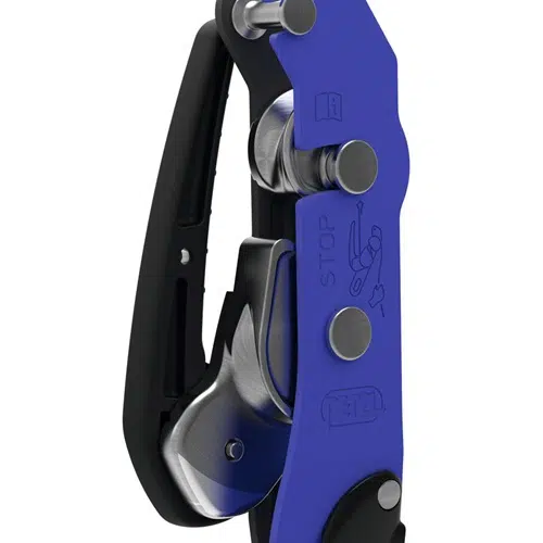 Primer plano del dispositivo Descensor Petzl Stop que muestra su diseño azul y negro, con mecanismos plateados y un asa. La superficie presenta ilustraciones junto con la palabra "STOP", que enfatiza su función de proporcionar un descenso seguro y controlado por cuerda para actividades de escalada.