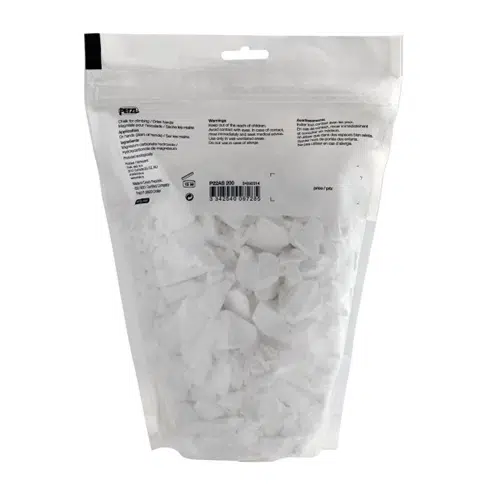 Bolsa transparente con cierre hermético que contiene tizas blancas grandes, que se utilizan normalmente para escalar. La parte posterior de la bolsa muestra instrucciones y advertencias impresas en negro, con la etiqueta Magnesio Petzl Power Crunch, conocida por mejorar el agarre.