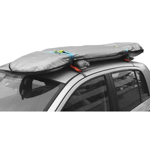 El perfil lateral del vehículo presenta una tabla de surf con una cubierta gris sujeta de forma segura al techo del automóvil con correas de color azul y naranja vibrantes, utilizando el innovador Parrilla Portaequipaje Inflable Sea To Summit Pack Rack.