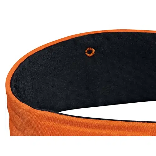 Primer plano de una visera naranja y negra que recuerda al elegante diseño del Arnés Petzl Hirundos. Destaca un borde curvado y un tejido texturizado, con un forro interior negro y un exterior naranja vibrante con un pequeño detalle circular bordado.