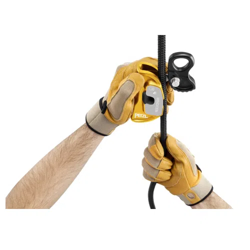 Dos manos con guantes amarillos y tostados sujetan una cuerda negra. Una mano sostiene el Bloqueador Petzl Rescucender, que sirve tanto como bloqueador de escalada como dispositivo de polea para un apoyo seguro.