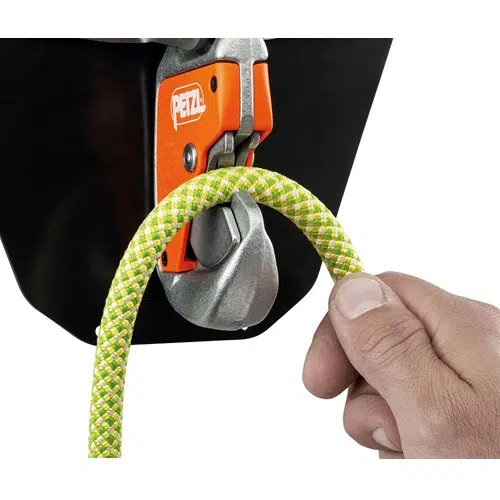 Una mano pasa con destreza una cuerda de escalada de color verde amarillento por un dispositivo de seguridad naranja y plateado con la inscripción "PETZL", que muestra el Mosquetón Petzl con Base Easytop Wall sobre un fondo oscuro. Esta disposición resalta la importancia de contar con un equipo de seguridad de alta calidad para la escalada.