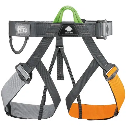 El arnés de escalada Arnés Petzl Pandion de Petzl cuenta con perneras de color gris y naranja, una presilla de seguridad de color verde y una etiqueta con la leyenda "Attach Here" cerca del cinturón. Las perneras y la cintura cuentan con hebillas ajustables para un ajuste seguro.