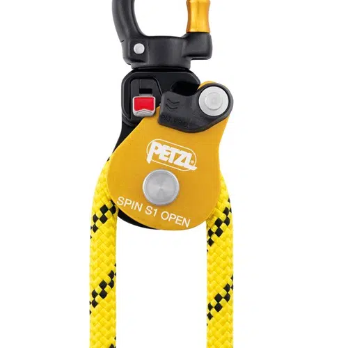 Una vista detallada del Polea Industrial Simple Petzl Spin S1 Open revela una cuerda amarilla y negra tejida a través de la polea. El dispositivo en sí es amarillo, lleva el logotipo de Petzl e incluye un mecanismo de bloqueo rojo junto con un punto de sujeción de metal negro.