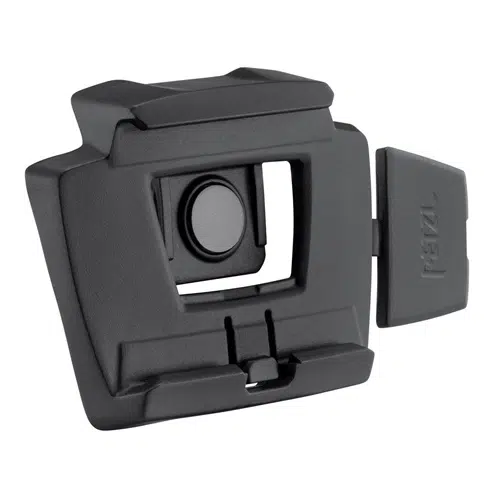 El soporte para linterna Petzl Slot Adapt es un soporte de montaje rectangular de color negro que presenta una ranura central y una pequeña tapa extraíble en el lateral. Incorpora un mecanismo de botón en el medio y características de diseño angulares que lo hacen adecuado para su fijación a diversos equipos o superficies.