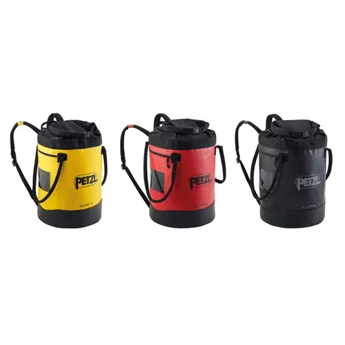 Se muestran tres bolsos tipo cubo con correas para el hombro: uno amarillo, uno rojo y uno negro. Cada Petzl Bucket tiene una parte superior negra con cierre de cordón, un bolsillo transparente en la parte delantera y el icónico logotipo de Petzl para darle ese estilo distintivo de Bolso Autoportante.