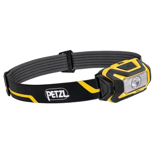 La linterna frontal Petzl Aria 1 de 350 lm es una linterna frontal negra y amarilla con una correa ajustable que lleva la marca "Petzl". Tiene una sola luz LED y un botón en la parte superior para su funcionamiento. El diseño incluye una protección resistente alrededor de la luz y una correa para un ajuste seguro.