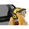 Una persona con guantes marrones ajusta la Linterna Frontal Petzl Duo Z1 360lm, una linterna frontal amarilla y negra con una correa negra. La linterna frontal está fijada sobre una superficie oscura y muestra de forma destacada su logotipo.