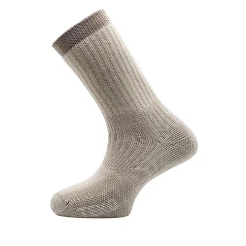Un calcetín de lana beige y gris, que recuerda al Calcetín Teko Ecohike Light Half Cushion 2.0, se presenta sobre un fondo blanco liso. Tiene una textura acanalada con una sutil gradación de color desde el pie hasta la parte superior, donde una banda gris adorna el puño. La zona de los dedos presenta de forma destacada el logotipo de la marca.