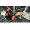 Una persona ataviada con un casco colorido y equipo de seguridad trepa un árbol, asegurada con cuerdas, arneses y la Cinta para Salvarramas Petzl Naja. Entre ramas y hojas, su ascenso aventurero es captado desde arriba.