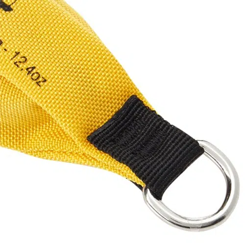 Primer plano de una correa de tela amarilla con costuras y texto negros, que recuerda a un diseño de Petzl, con un anillo D de metal unido al extremo.