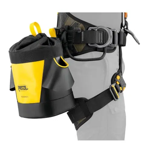 La Bolsa Portaherramientas Petzl Toolbag 6 en color amarillo y negro se fija firmemente a la cintura de una persona con un sistema de arnés, equipado con correas y hebillas ajustables, específicamente diseñadas para escalar o tareas similares.