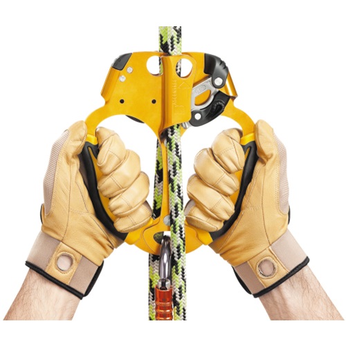 Dos manos con guantes de cuero color canela sujetan un bloqueador Petzl Doble Ascentree amarillo y negro asegurado con un mosquetón a una cuerda de escalada verde y negra, ideal para tareas de escalada o acceso por cuerda.