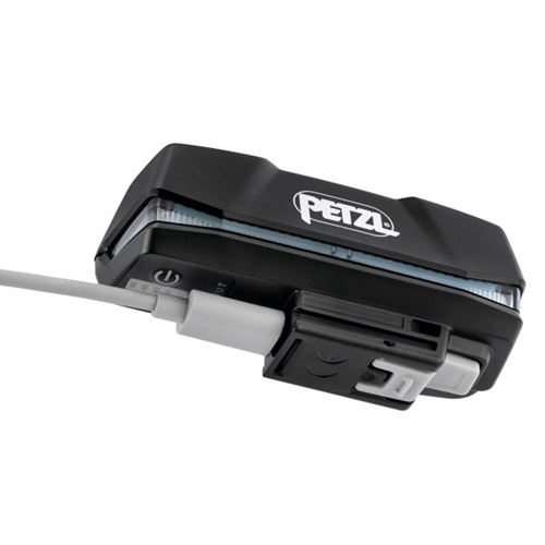 Se muestra una linterna frontal Petzl negra, elegante y compacta, conectada a un cable USB blanco, con su marca visible en la parte superior. Está equipada con una batería recargable Petzl R1 de 3200 mAh para un rendimiento duradero.