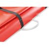 Primer plano de una lona roja plegada asegurada con una correa negra, que recuerda al diseño duradero empleado en la Petzl Nest Camilla para Rescates. Un asa blanca está unida al costado, visible contra la superficie roja. La textura del material parece resistente e impermeable.