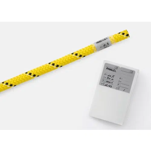 Una cuerda trenzada amarilla y negra enrollada se encuentra sobre una superficie blanca, acompañada de una etiqueta blanca que muestra información escrita a mano, similar al etiquetado preciso que se ve en el kit de marcado de cuerdas profesional Petzl.