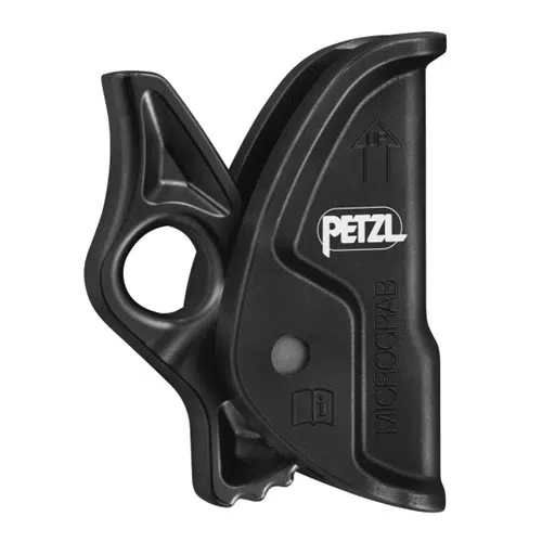 Imagen de un bloqueador de cambio Petzl Micrograb negro. El dispositivo presenta un diseño ergonómico con un lazo para la fijación y un mecanismo de palanca integrado para el ajuste de la empuñadura. Se muestra el logotipo de Petzl prominente, junto con una flecha que apunta hacia arriba.