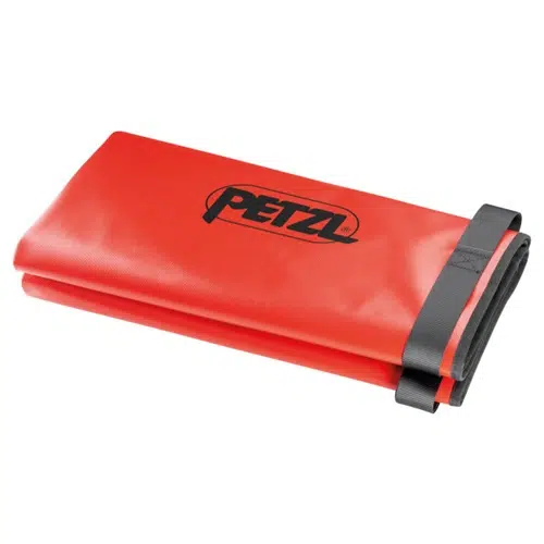 Una lona roja, similar al Petzl Bolso de Transporte Camilla Nest, está cuidadosamente doblada y sujeta con una correa negra. El nombre de la marca se muestra en negro en la superficie superior y los bordes de la lona están reforzados para mayor durabilidad.