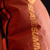 Primer plano de una bolsa impermeable de color naranja, que muestra gotas de agua en su superficie. La mochila impermeable Sea To Summit Big River Dry Backpack de 50 l incluye correas negras y tiene un texto amarillo destacado que dice "SEA TO SUMMIT".
