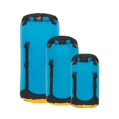 Tres bolsas impermeables en tonos de azul con correas negras y fondos amarillos, similares a la Bolsa de Compresión Sea To Summit Evac Compression Dry Bag, están dispuestas verticalmente sobre un fondo blanco liso.
